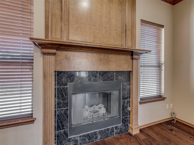 room details featuring a tiled fireplace, baseboards, and wood finished floors