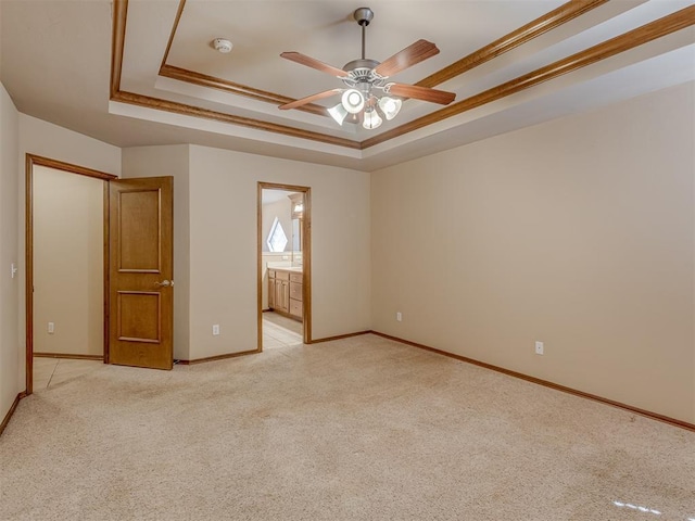 spare room with baseboards, a tray ceiling, ornamental molding, and light colored carpet