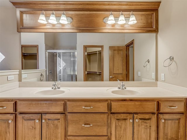 bathroom featuring double vanity, a shower stall, and a sink