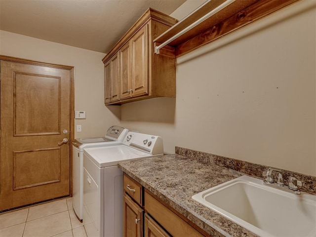 laundry room featuring washing machine and dryer, cabinet space, a sink, and light tile patterned flooring