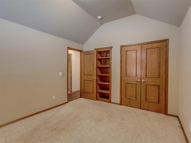 unfurnished bedroom with carpet floors, baseboards, and vaulted ceiling