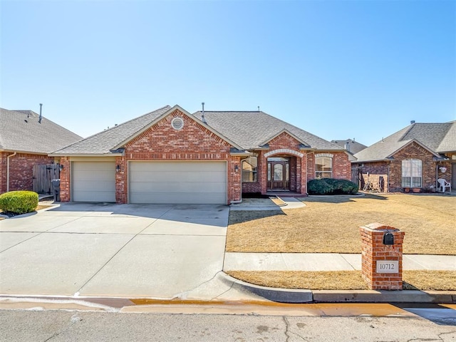 view of front of home with driveway, a garage, brick siding, roof with shingles, and a front yard