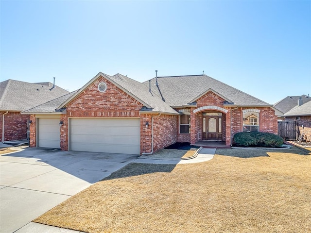 view of front of house featuring an attached garage, a shingled roof, brick siding, concrete driveway, and a front yard