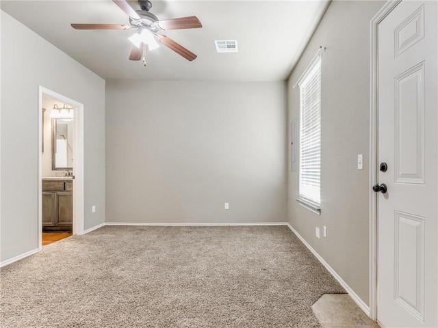 unfurnished room with sink, ensuite bathroom, light colored carpet, and ceiling fan