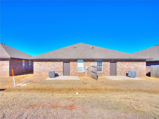 rear view of property featuring central air condition unit, a patio, and a lawn