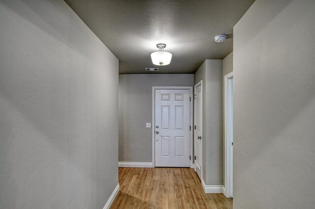 corridor with visible vents, baseboards, and wood finished floors