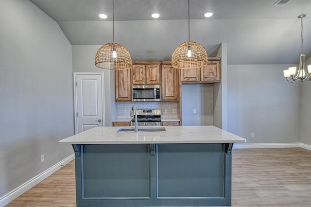 kitchen with appliances with stainless steel finishes, light stone countertops, light wood-style floors, and a sink