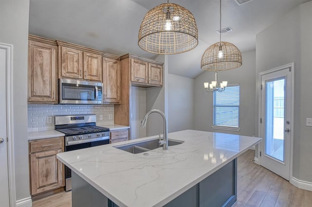 kitchen featuring visible vents, a sink, stainless steel appliances, light wood-style floors, and decorative backsplash