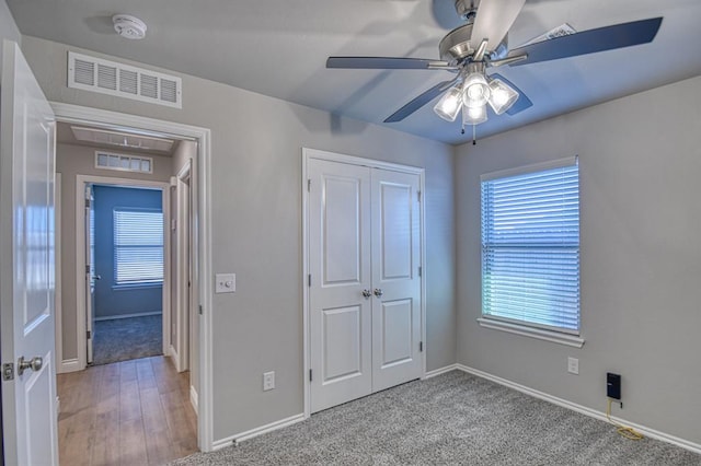 unfurnished bedroom featuring visible vents, a closet, carpet flooring, baseboards, and ceiling fan