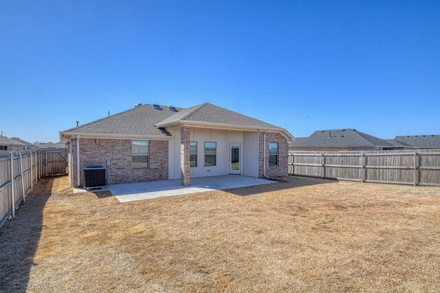 back of property featuring brick siding, cooling unit, a fenced backyard, a yard, and a patio