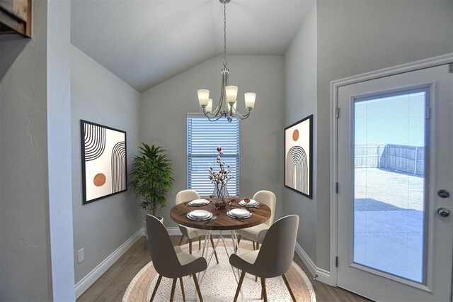 dining room featuring baseboards, a notable chandelier, wood finished floors, and vaulted ceiling