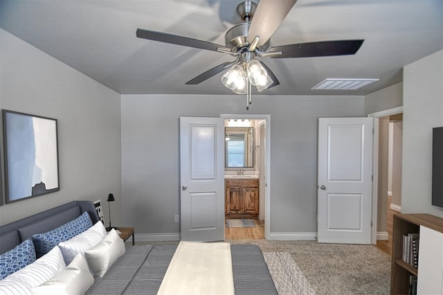 bedroom with visible vents, a sink, ensuite bath, baseboards, and ceiling fan