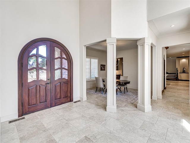 foyer entrance with a high ceiling, visible vents, baseboards, french doors, and decorative columns