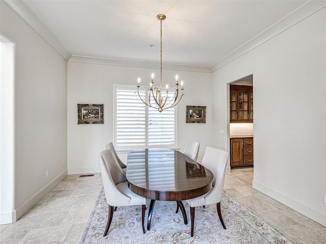 dining room featuring a chandelier, stone tile flooring, crown molding, and baseboards