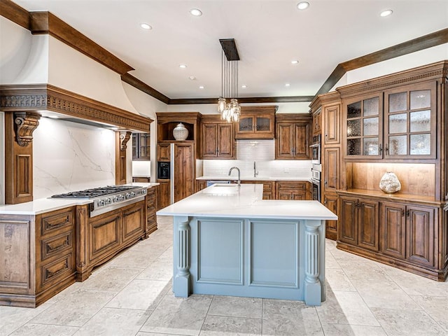 kitchen featuring light countertops, custom range hood, appliances with stainless steel finishes, glass insert cabinets, and a kitchen island with sink