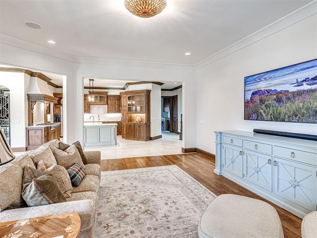 living room with recessed lighting, light wood-style flooring, baseboards, and ornamental molding