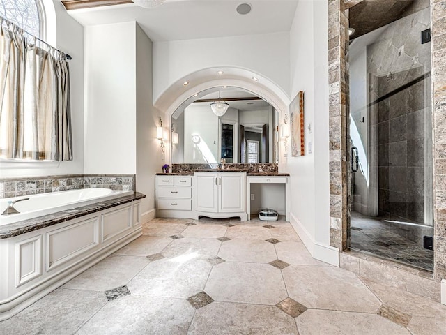 bathroom featuring a stall shower, baseboards, a bath, and vanity