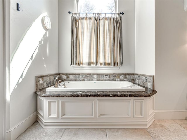 full bathroom with tile patterned flooring, baseboards, and a bath