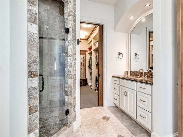 full bathroom featuring a shower stall, baseboards, a walk in closet, and vanity