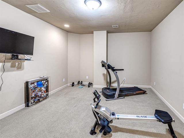 exercise area featuring baseboards, visible vents, and carpet flooring