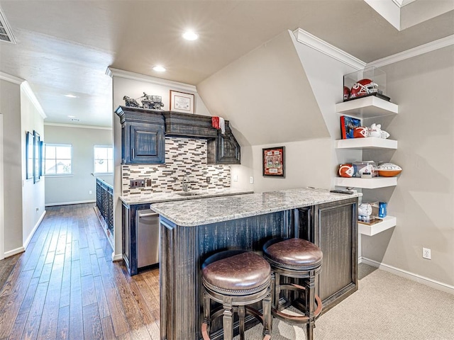 kitchen with a breakfast bar, crown molding, tasteful backsplash, light stone countertops, and baseboards