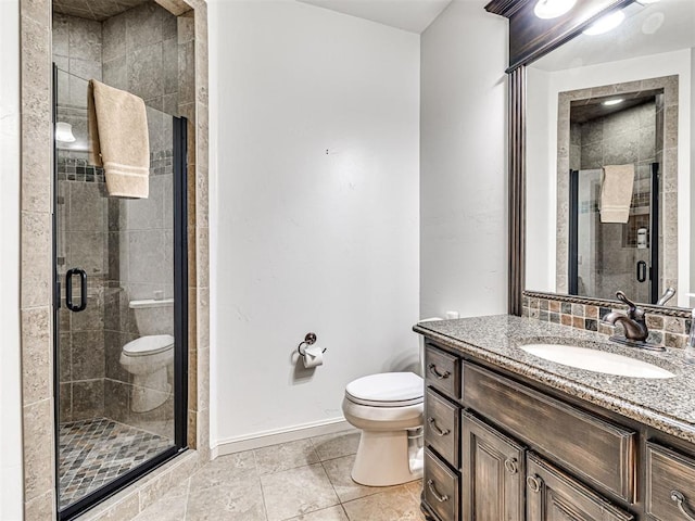 full bathroom featuring a stall shower, vanity, toilet, and baseboards