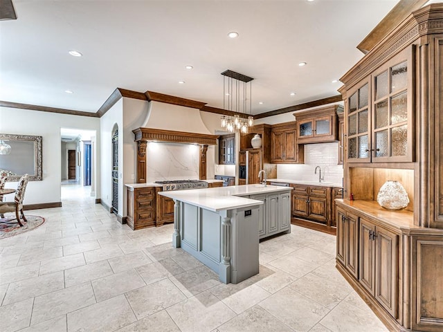 405 Flint Ridge Ct, Norman, OK 73072 - kitchen with crown molding, light countertops, backsplash, a large island with sink, and brown cabinets
