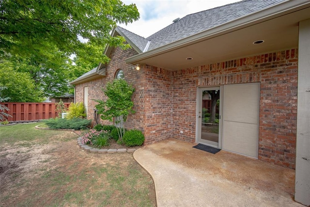 1601 Vandivort Pl, Edmond, OK 73034 - property entrance with fence, roof with shingles, brick siding, and a patio area