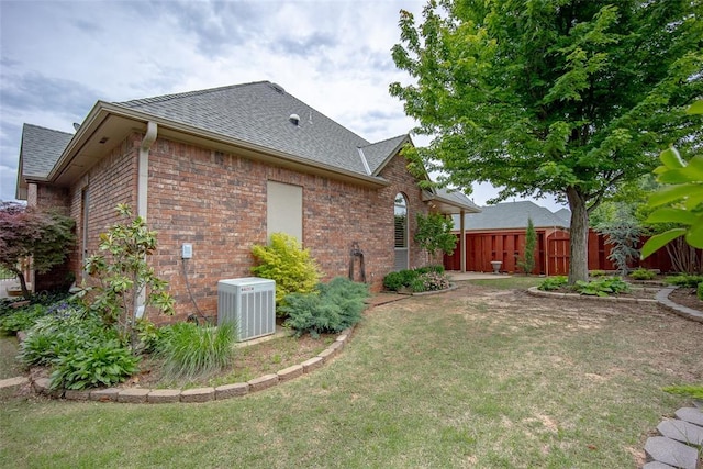 1601 Vandivort Pl, Edmond, OK 73034 - view of side of property with central AC unit, brick siding, and a shingled roof