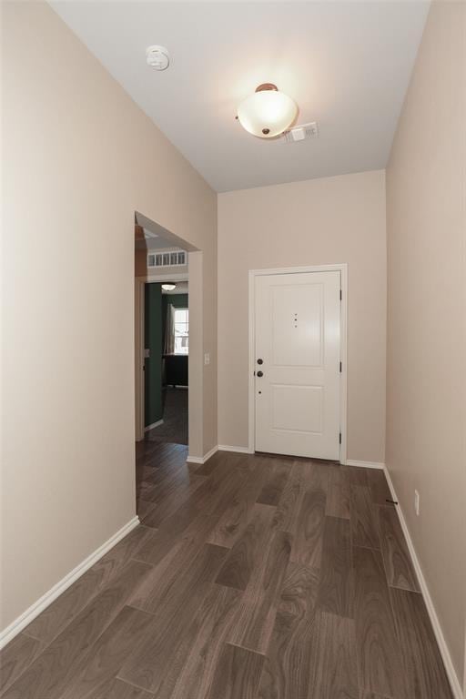 hall with visible vents, baseboards, and wood finished floors