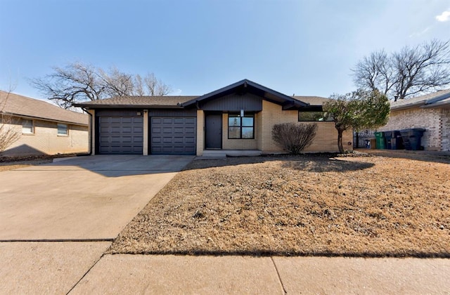 mid-century inspired home with a garage, concrete driveway, and brick siding