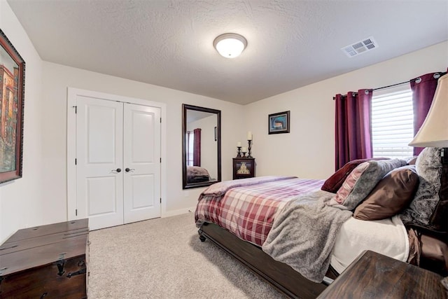 bedroom featuring carpet, a closet, visible vents, and a textured ceiling