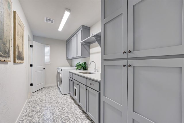 washroom featuring a sink, visible vents, baseboards, independent washer and dryer, and cabinet space