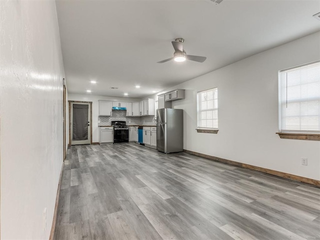 kitchen with appliances with stainless steel finishes, decorative backsplash, light wood-type flooring, and ceiling fan