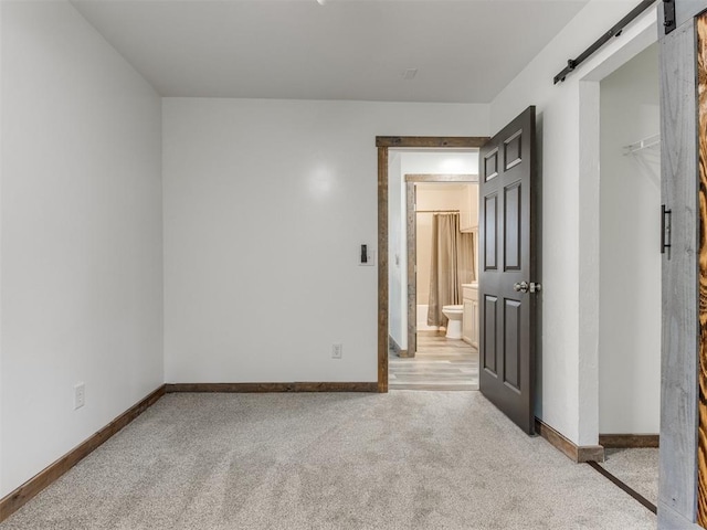 unfurnished room with a barn door and light colored carpet