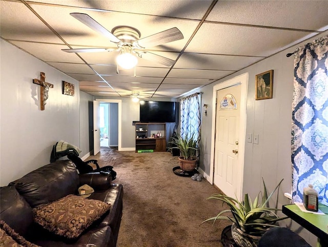 carpeted living area with a paneled ceiling, a ceiling fan, and baseboards