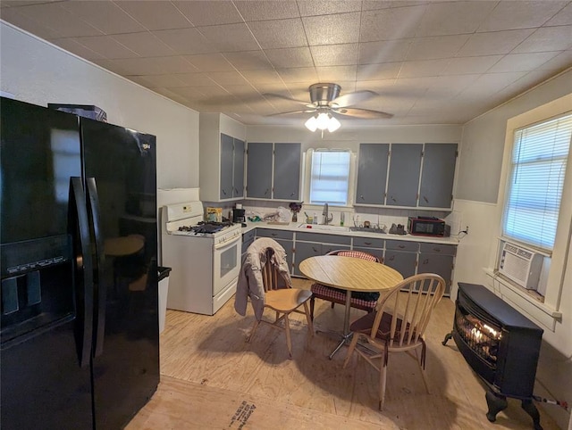 kitchen featuring cooling unit, a sink, light countertops, black fridge, and white gas range