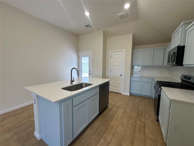 kitchen with light wood finished floors, visible vents, a sink, stainless steel appliances, and backsplash