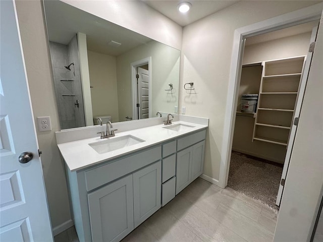 full bathroom featuring baseboards, a sink, toilet, and double vanity