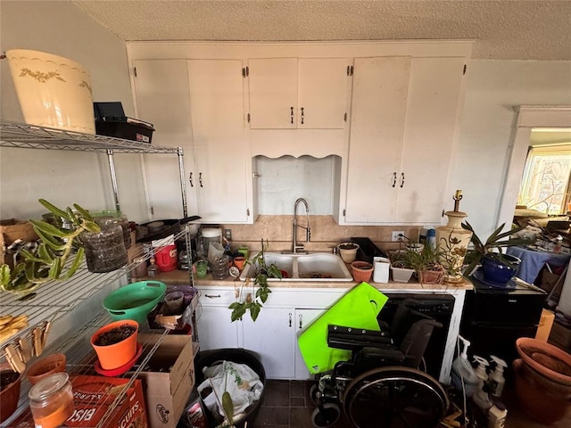 kitchen featuring white cabinets, a sink, and a textured ceiling