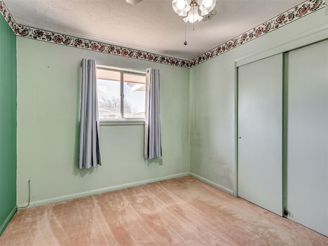 unfurnished bedroom featuring carpet, a closet, a textured ceiling, and baseboards