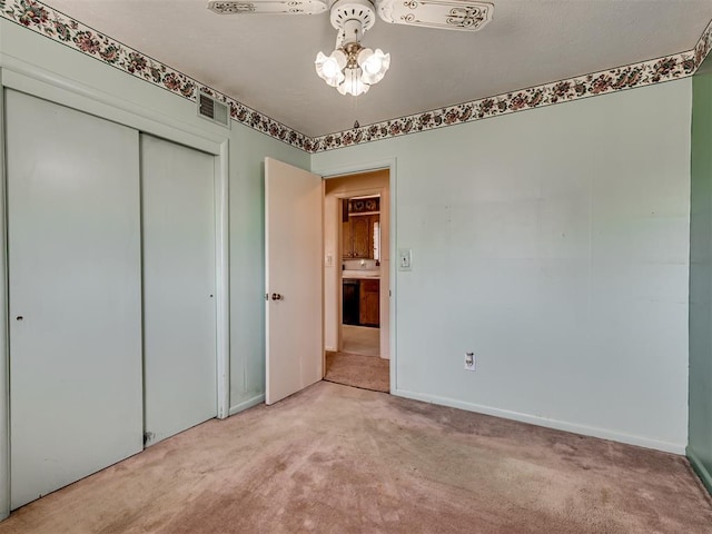 unfurnished bedroom featuring light carpet, a closet, visible vents, and baseboards