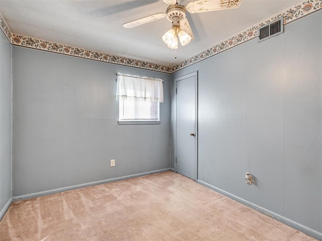 carpeted spare room with visible vents and ceiling fan