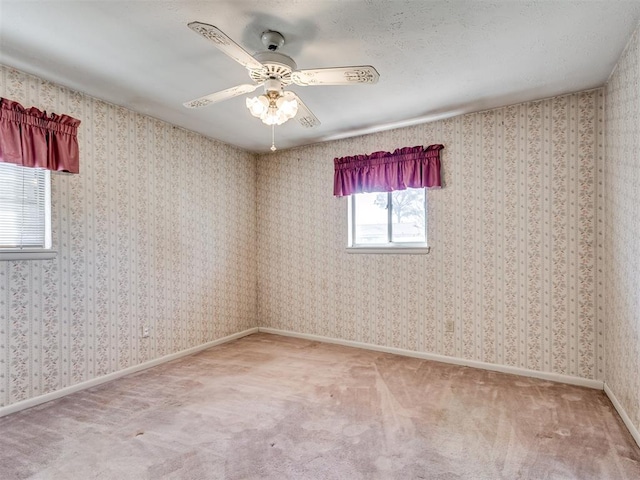 carpeted spare room with a ceiling fan, baseboards, and wallpapered walls