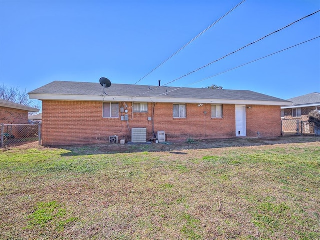 rear view of property with brick siding, a lawn, cooling unit, and fence