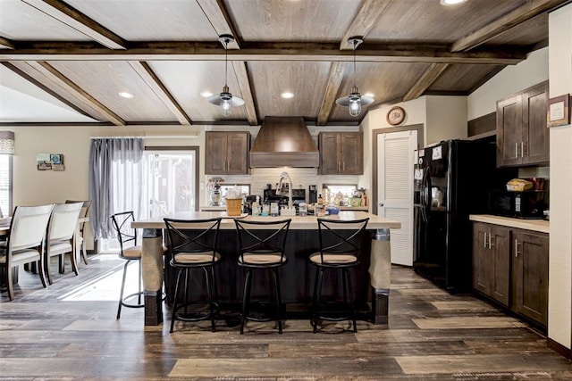 kitchen with dark brown cabinetry, black appliances, premium range hood, and a wealth of natural light