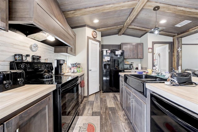 kitchen with lofted ceiling with beams, butcher block countertops, wood finished floors, black appliances, and premium range hood