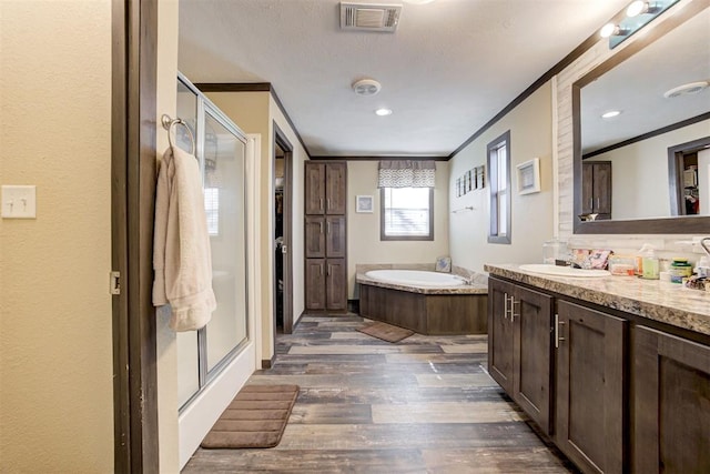 bathroom with a garden tub, ornamental molding, wood finished floors, and visible vents