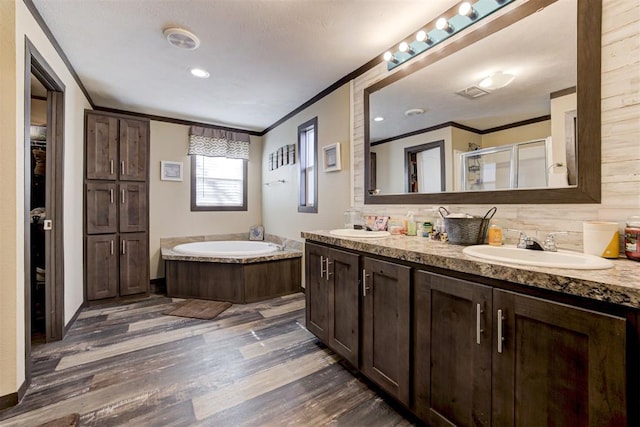 full bathroom featuring a garden tub, a shower stall, ornamental molding, and wood finished floors