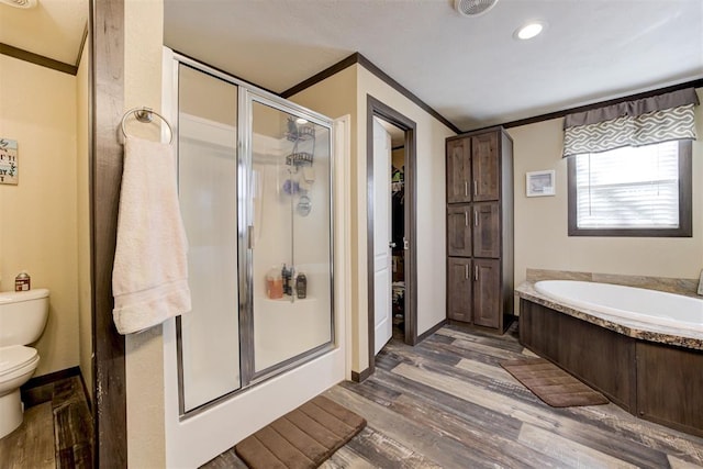 bathroom with a garden tub, toilet, wood finished floors, ornamental molding, and a stall shower